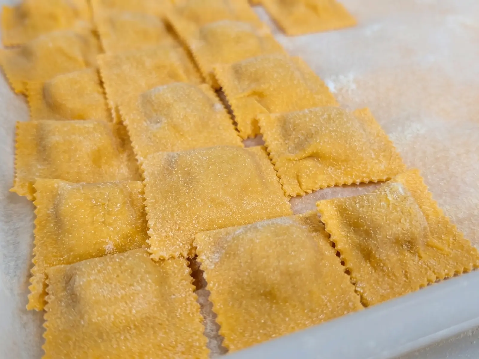 Fresh ravioli resting on floured parchment